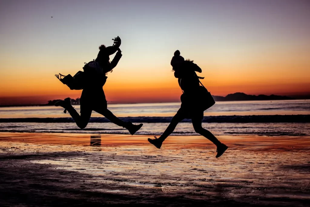 夕焼けにジャンプしている2人の女性